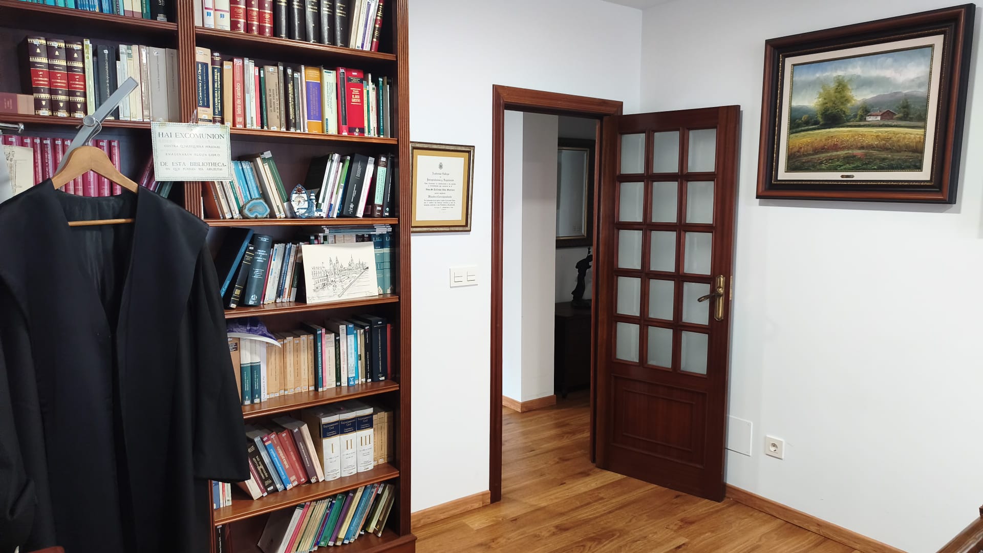 Biblioteca jurídica del despacho con la toga profesional